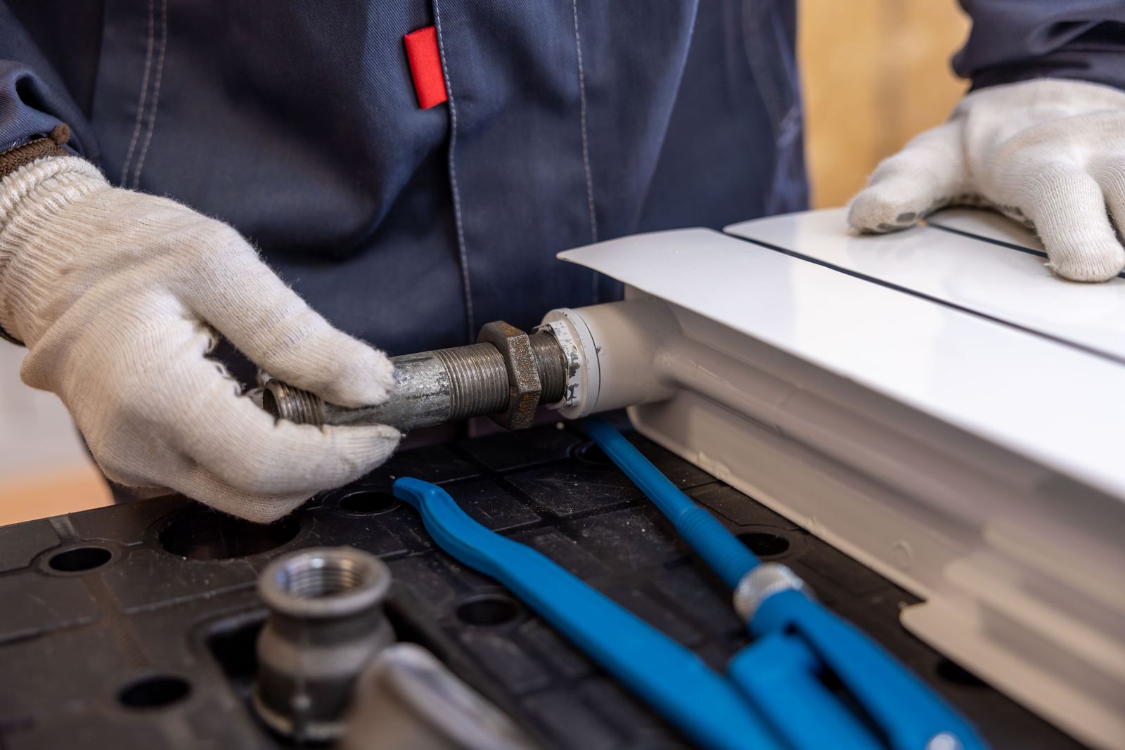 Uniformed plumber with gloves fitting a pipe